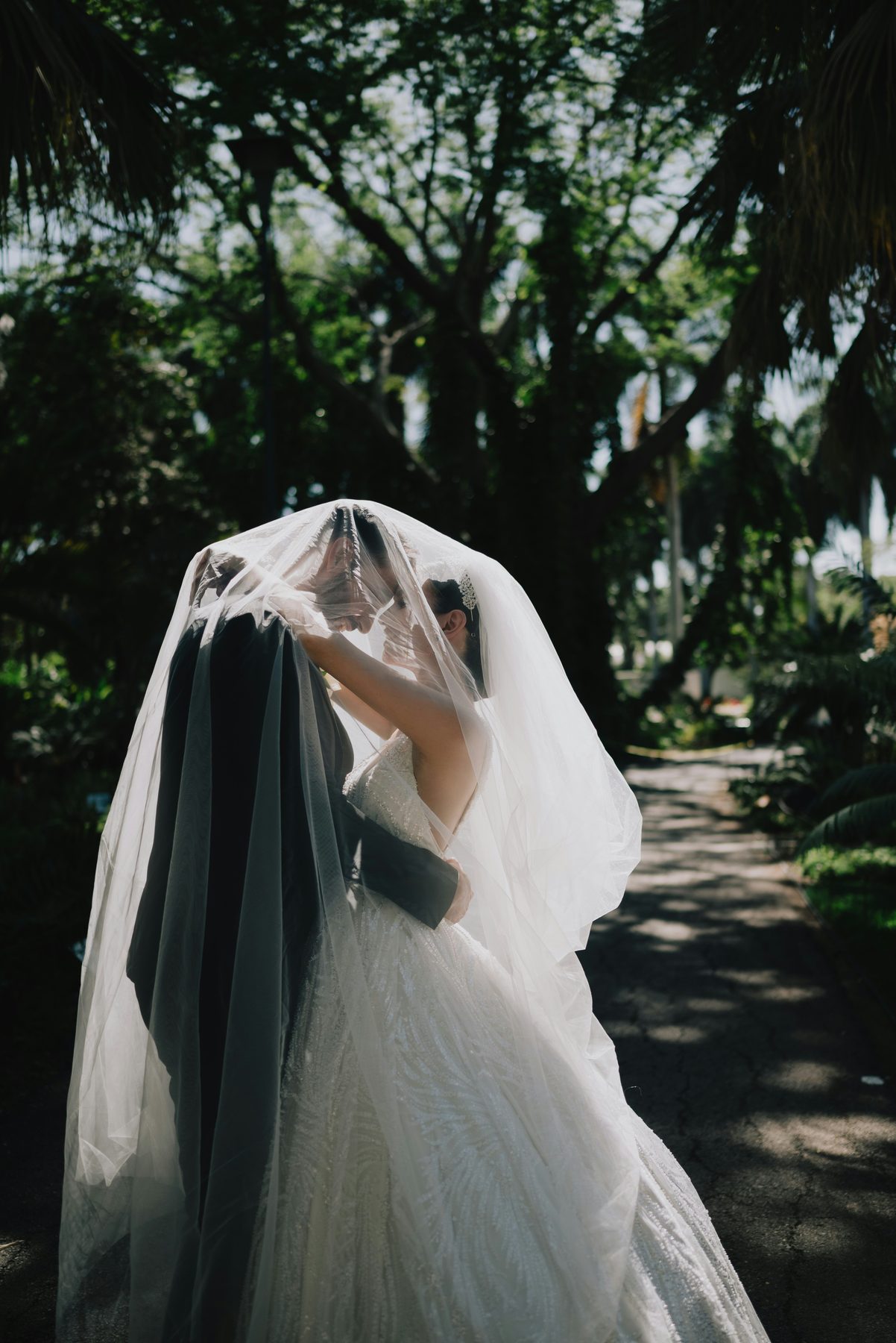 A couple beneath a bridal veil on their wedding day