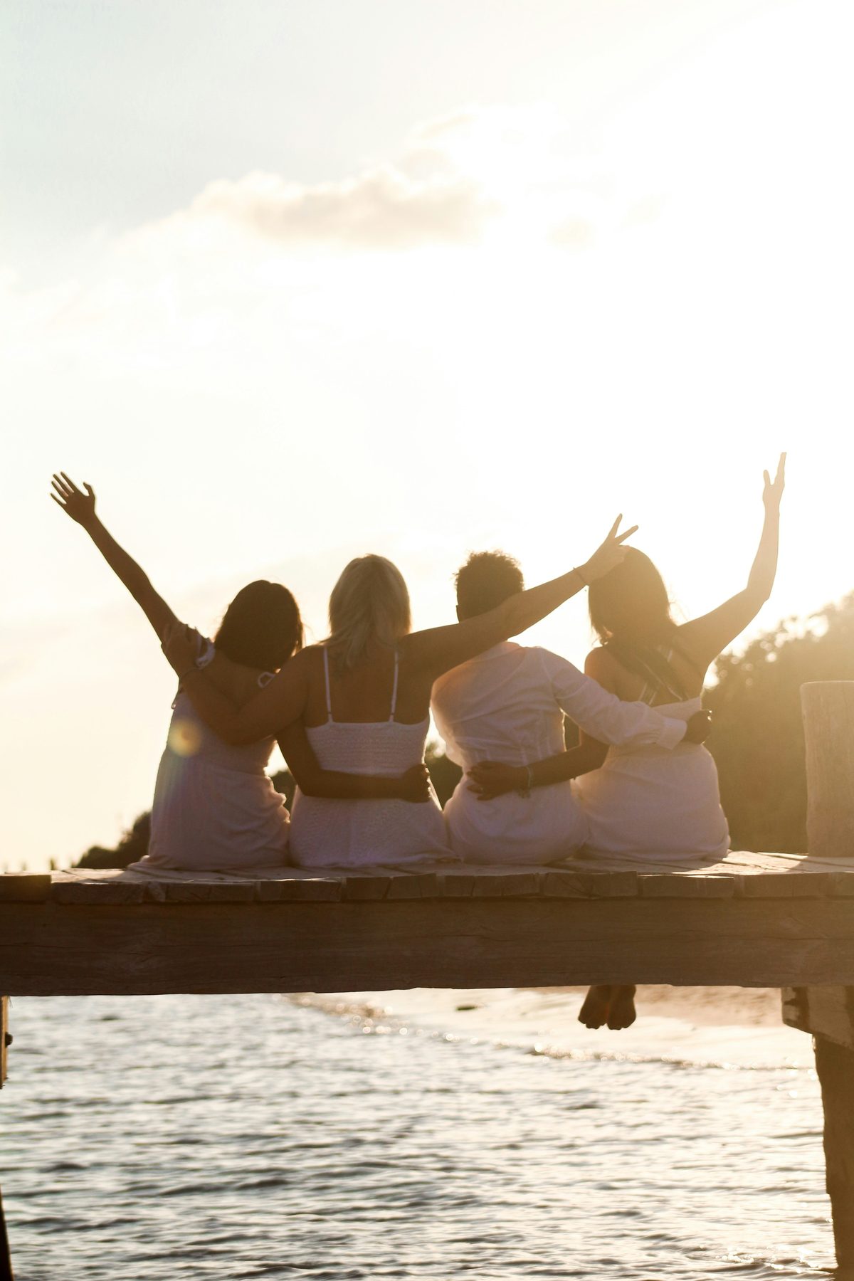 Friends sitting together on a jetty by the sea